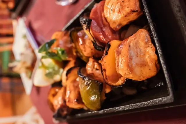 Chicken tikka and peppers coming out of the tandoor in a cast-iron server